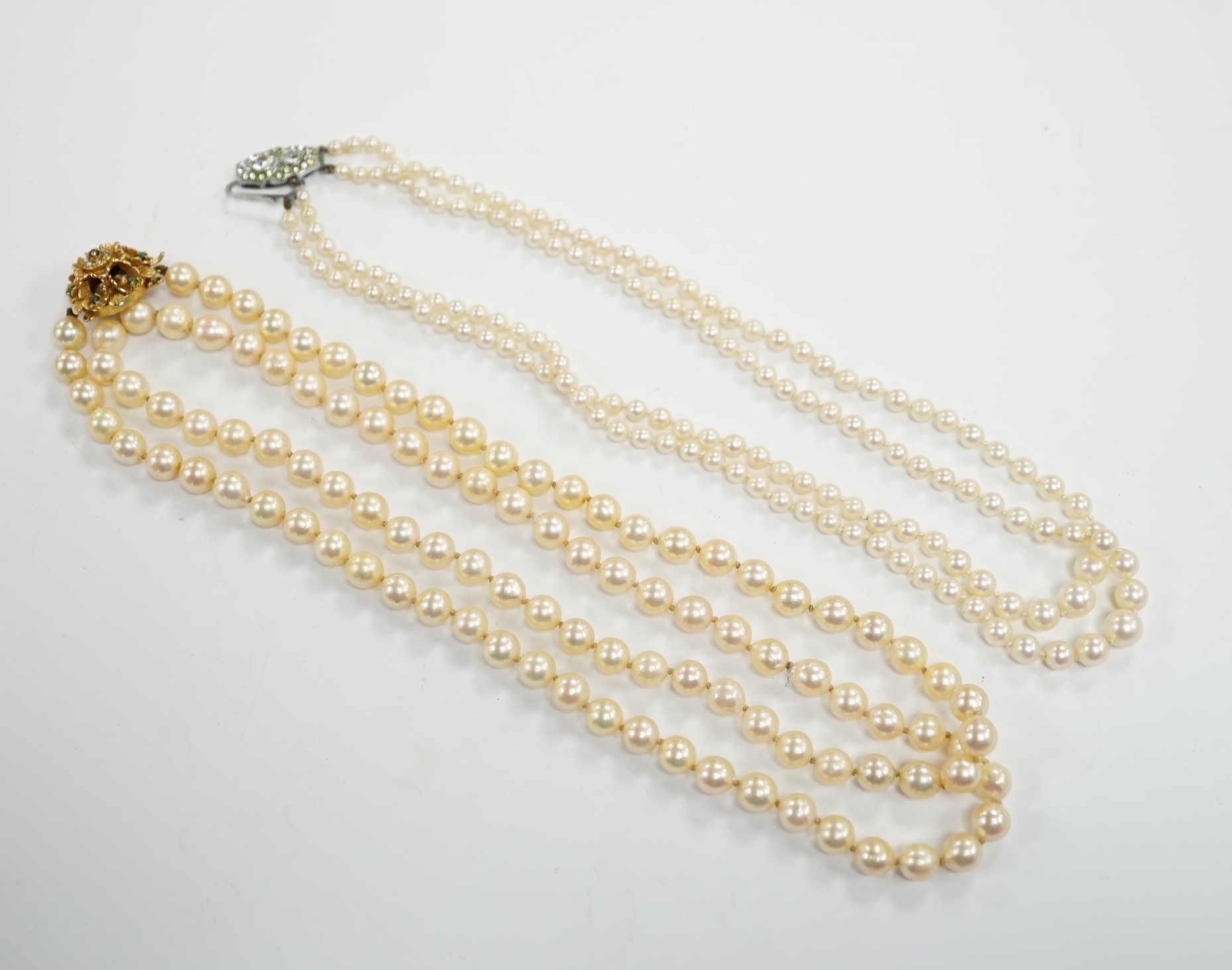 A single strand cultured pearl necklace, with turquoise? and seed pearl set 9ct clasp, 56cm and a double strand cultured pearl necklace with paste set clasp.